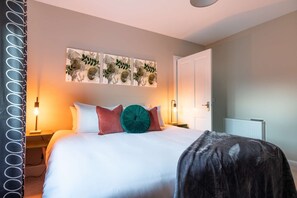 A bedroom with a bed, a nightstand, a wall-mounted lamp, and a radiator. - Ness at the Park, Inverness (Inverness)