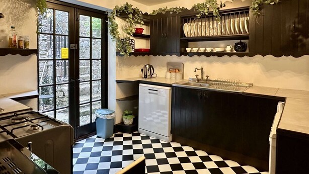 A compact kitchen with a checkered floor, a refrigerator, a sink, and a stove.