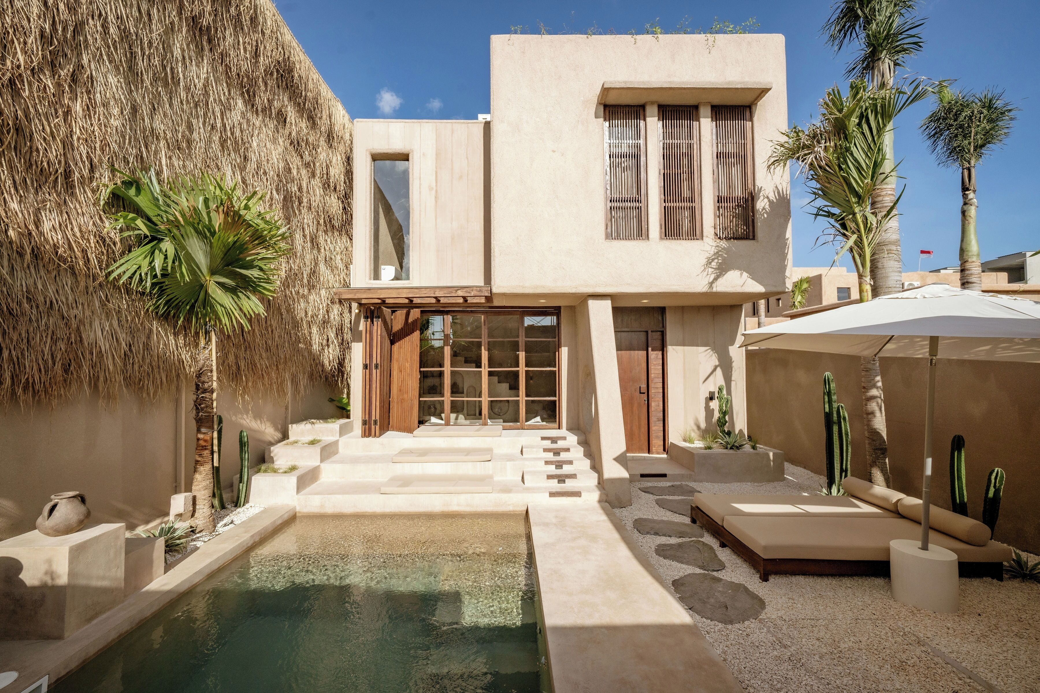 A modern building with a pool, steps leading to the entrance, and cacti in the garden.