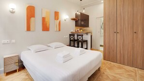 Een slaapkamer met een bed, nachtkastjes, een garderobe en een kitchenette.
