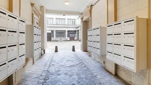 Een gang met aan beide kanten brievenbussen, die leidt naar de ingang van een gebouw.
