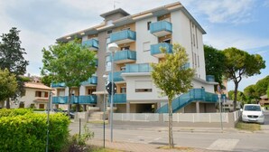 Un edificio residenziale a più piani con balconi, un'area di parcheggio e un percorso pedonale.