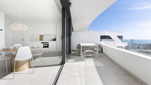 Un balcon moderne doté d’un espace repas, d’une cuisine et offrant une vue sur la ville.