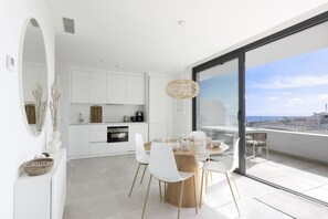 A modern kitchen with white cabinets and a dining area with a round table and white chairs. - Elegant Luxury Suite with Terrace in Higueron (Fuengirola)