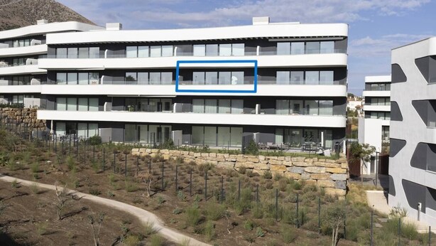 Un immeuble à plusieurs étages, doté d’un toit plat, de grandes fenêtres et d’un mur de soutènement en pierre.