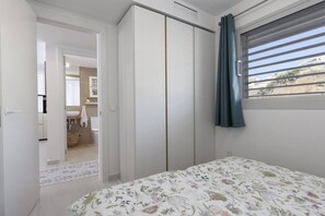 Een slaapkamer met een bed, een kledingkast en een raam met gordijnen.