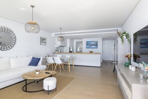 Een moderne woonkamer met een bank, salontafel en eethoek.