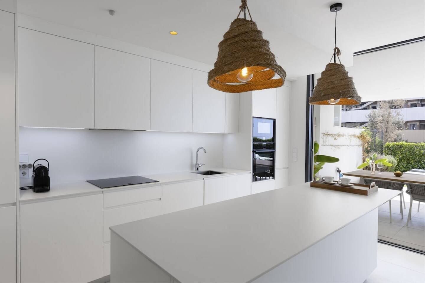 Een moderne keuken met witte kasten, een centraal eiland en twee hangende吊灯