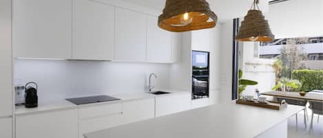 Een moderne keuken met witte kasten, een centraal eiland en twee hangende吊灯