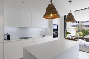 A modern kitchen with white cabinetry, a central island, and two hanging pendant lights.