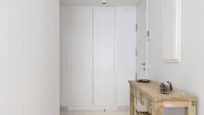 A hallway with a white wardrobe, a wooden console table with decorative items, and a white door. - Exclusive Apartment with Garden in Higueron (Fuengirola)