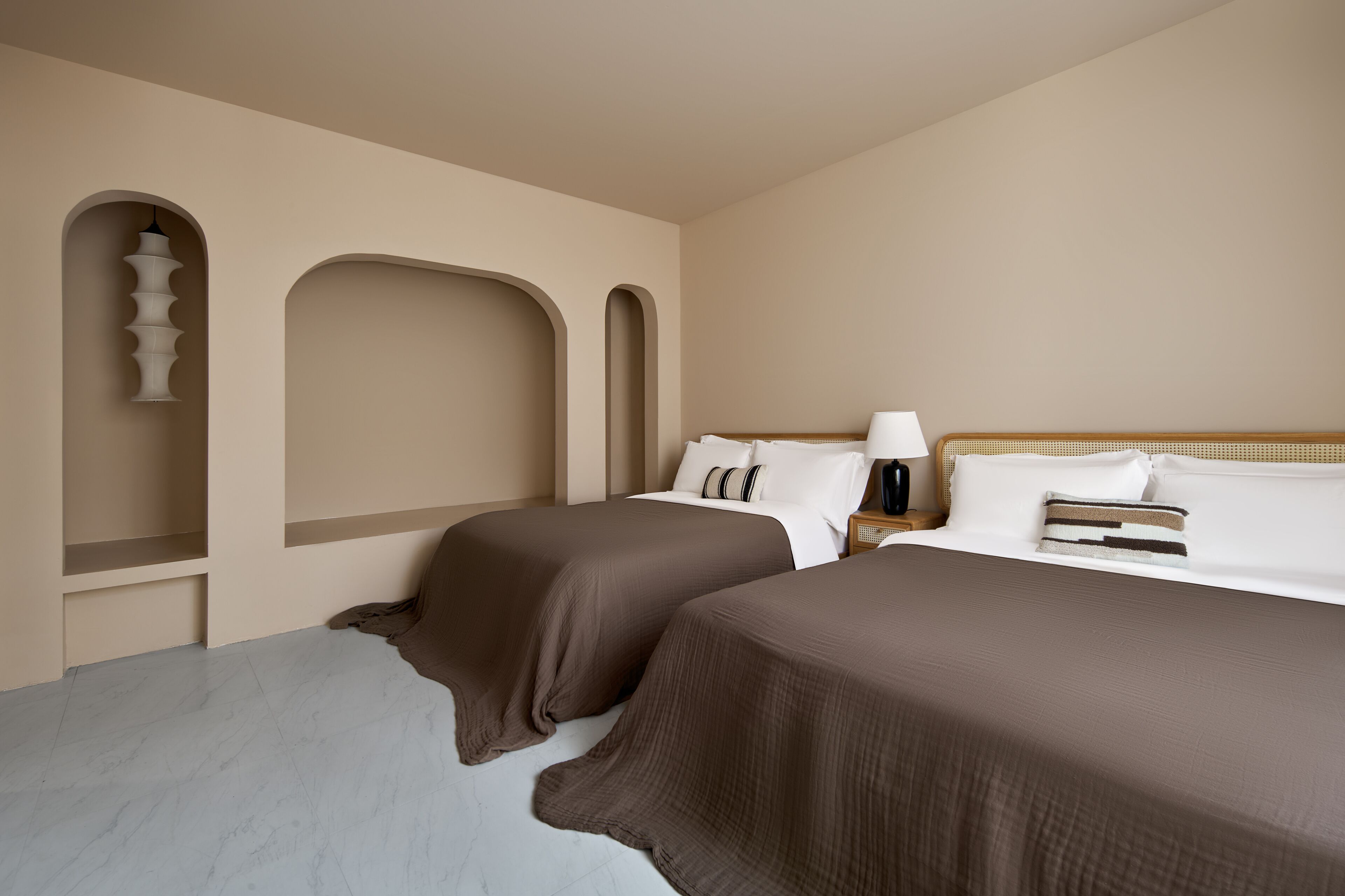 Una habitación de hotel con dos camas, una mesita de noche y una lámpara fijada a la pared.