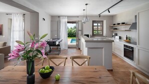Une cuisine moderne avec un îlot central, une table à manger en bois et une vue sur une piscine.