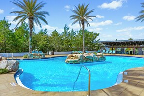 Ein Swimmingpool mit Palmen, Liegestühlen und einem überdachten Bereich.