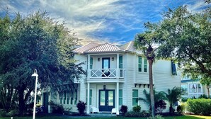 A two-story house with a balcony, surrounded by greenery and a clear sky. - Jessa Blu by AvantStay | Walk to Beach | Pool + Gym (Santa Rosa Beach)