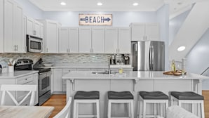 A modern kitchen with white cabinets, stainless steel appliances, and a central island with bar stools.
