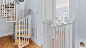 A staircase with white railings and wooden steps, leading to a room with a white door and a window with blinds.