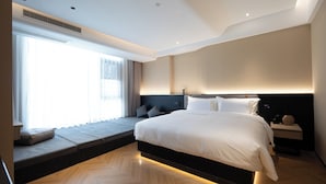 A modern bedroom with a large bed, built-in seating area, and a view of the outdoors. - See you soon at Ritz Rose Summer Hotel (Sanya)