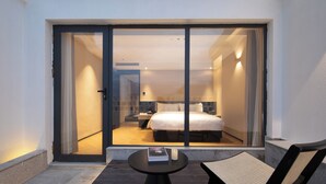 A hotel room with a bed, a nightstand, a lamp, and a view through a glass door. - See you soon at Ritz Rose Summer Hotel (Sanya)