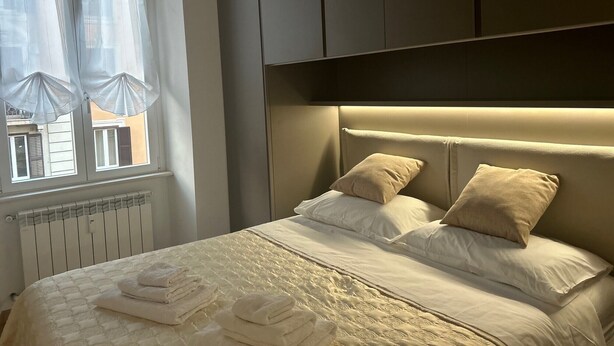 A bedroom with a bed, pillows, and a radiator. - Leonard Vatican House Deluxe  (Roma)