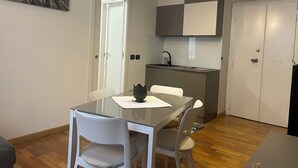 A modern kitchen with a built-in stove, a sink, and a small countertop. There is a dining table with chairs and a painting on the wall. - Leonard Vatican House Deluxe  (Roma)