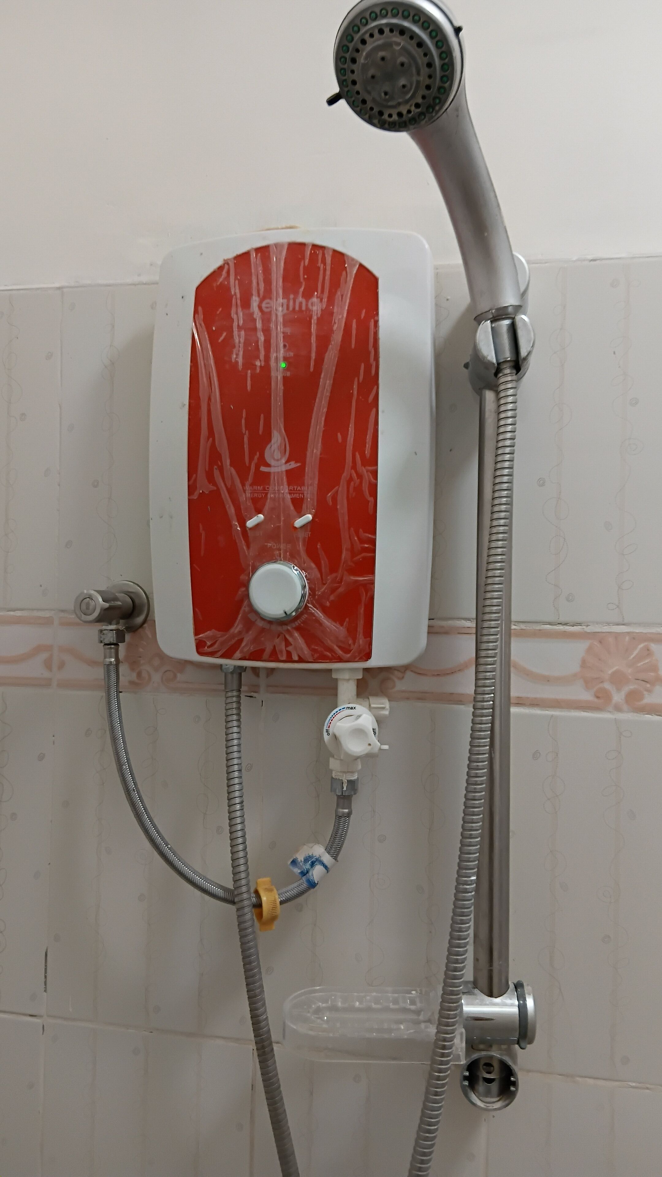 Ducha con panel de control rojo, cabezal de ducha de mano y manguera flexible.