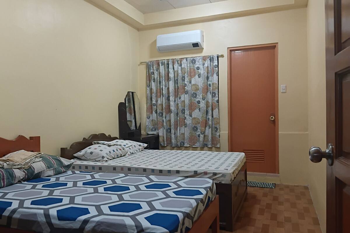 Ein Schlafzimmer mit einem Bett, einem Kleiderschrank, einem Spiegel und einer Klimaanlage.