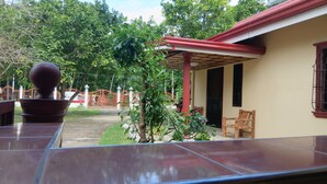 A covered patio area with a tiled floor, a potted plant, and a wooden chair. - Jovick Homestay (Siquijor)