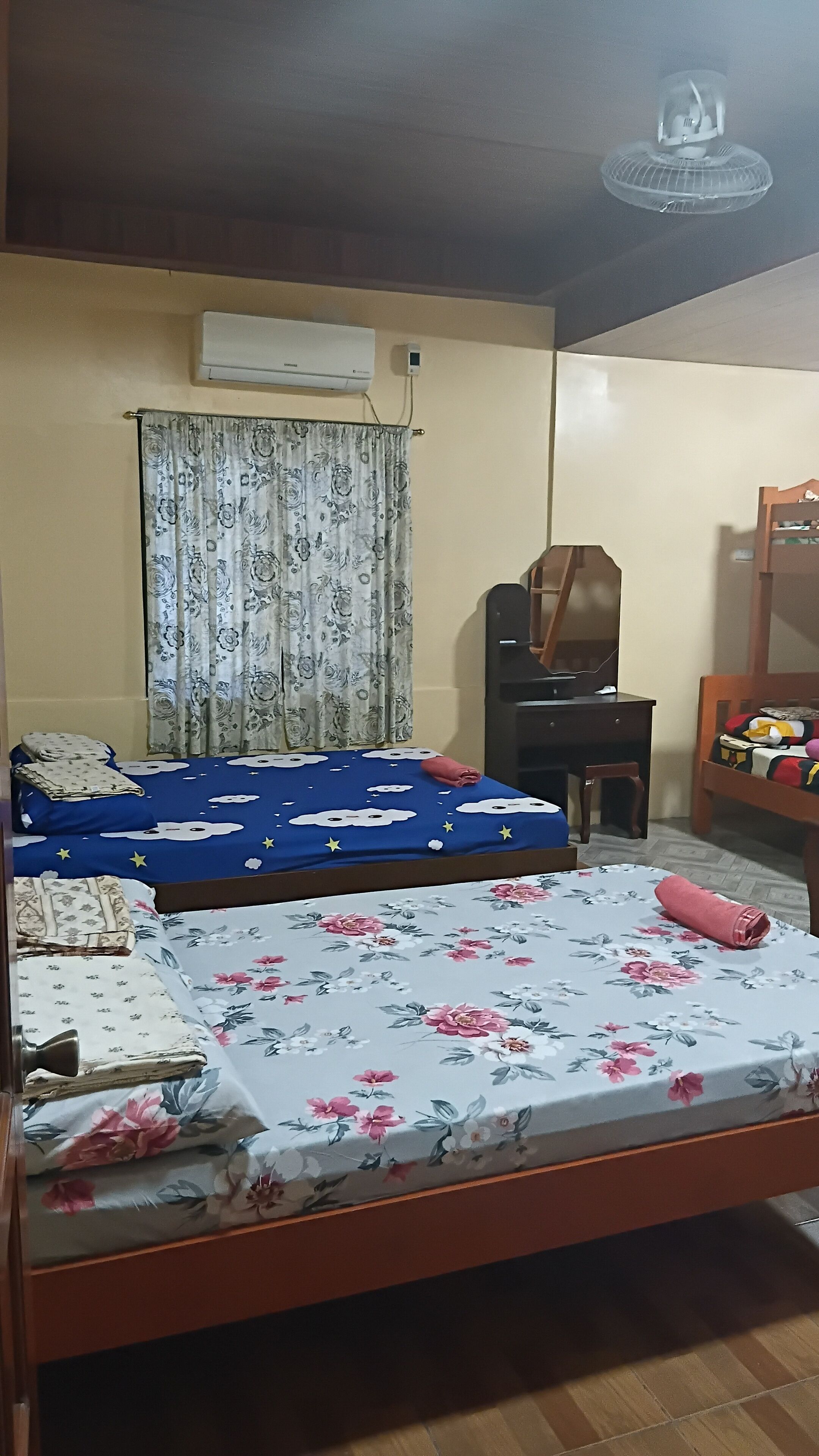 A bedroom with two beds, a desk, a chair, and a wardrobe.