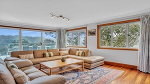 A spacious living room with a large sectional sofa, a coffee table, and a view of the outdoors through large windows.