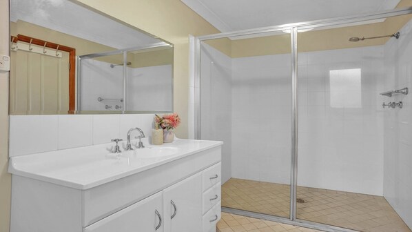 A bathroom with a white vanity, a glass shower enclosure, and a mirror above the vanity.