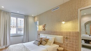 Ett hotellrum med en säng, ett runt träbord, en spegel och utsikt över omgivningarna.
