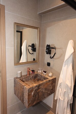 A bathroom with a marble sink, a large mirror, a towel rack, and a hairdryer mounted on the wall. - IPELHOME AVISSINIAS APARTMENTS (Athens)