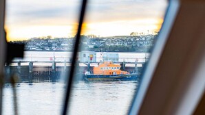 Uitzicht vanuit een raam op een haven met een boot aangemeerd aan een steiger.