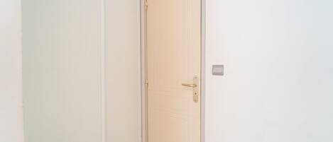 A closed door with a simple handle and a small light switch on the wall.