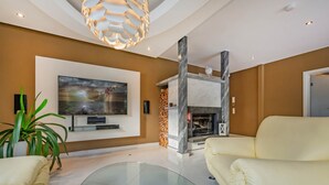A modern living room with a flat-screen TV, a fireplace, and a glass coffee table. - Villa Ost - Apartment Simone - high-quality designed domicile (Zinnowitz)