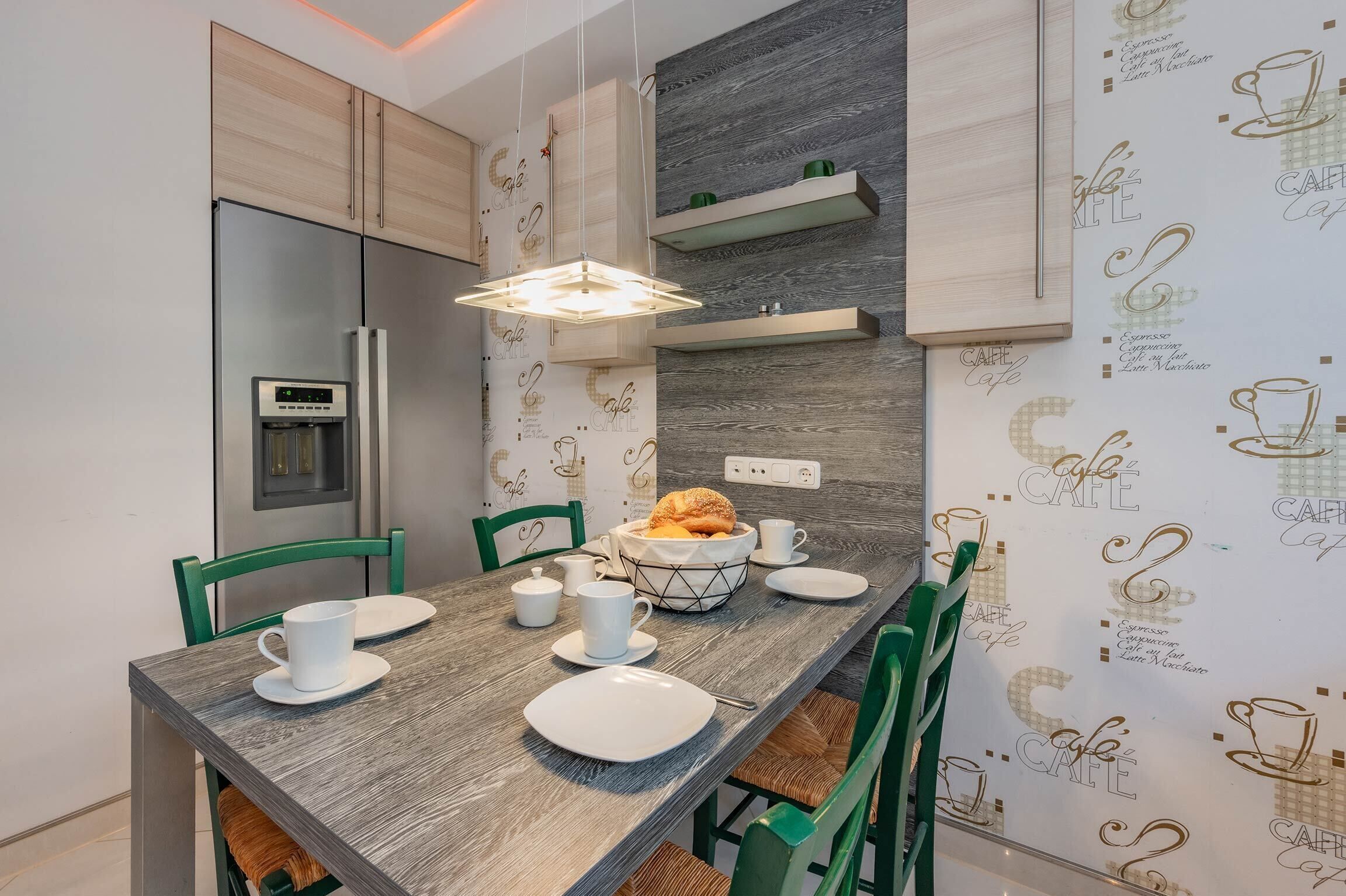 Une cuisine moderne avec une table à manger en bois, des chaises vertes et un four encastré.