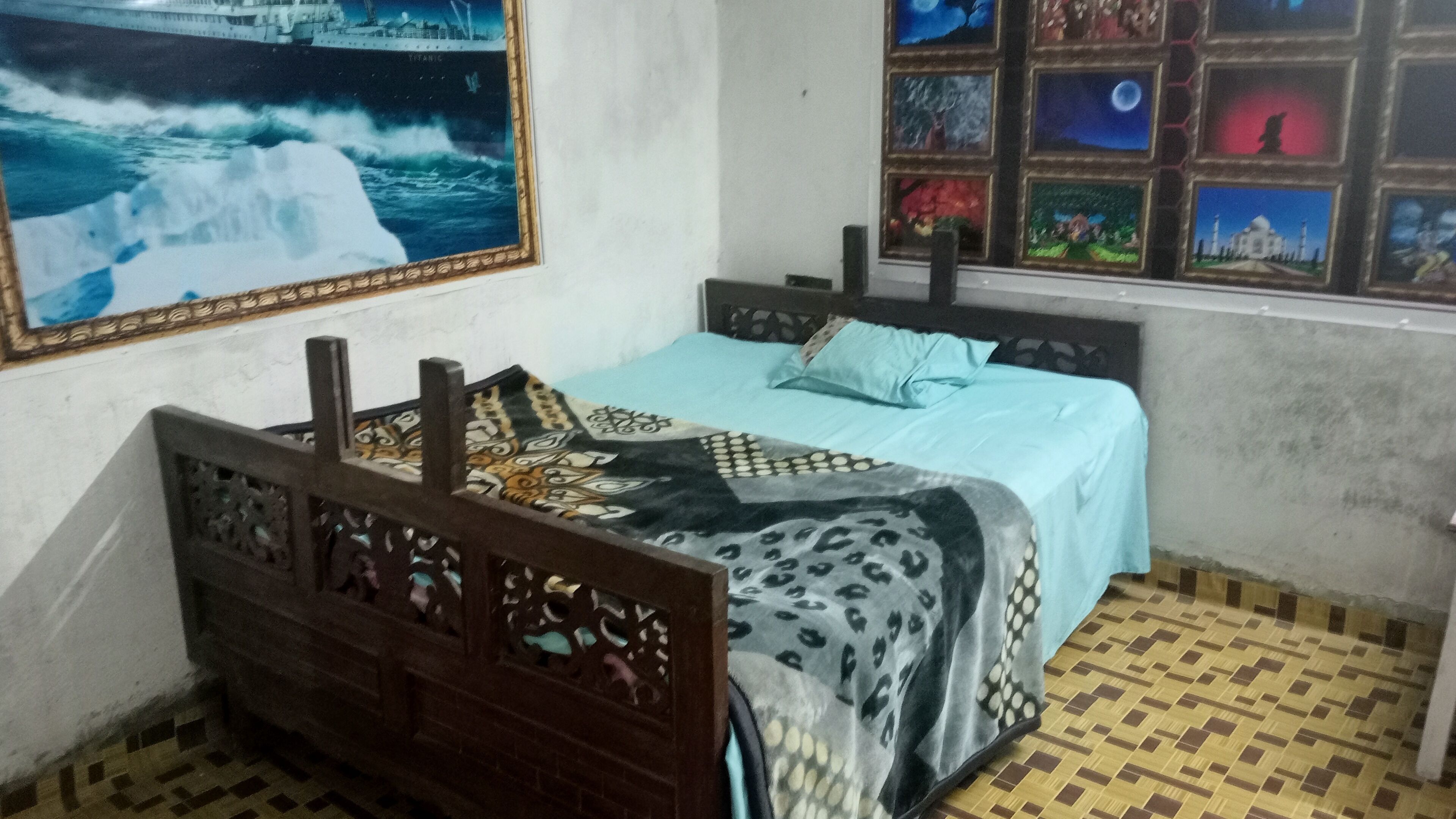 A room with a bed, a window with multiple pictures, and a large painting on the wall.