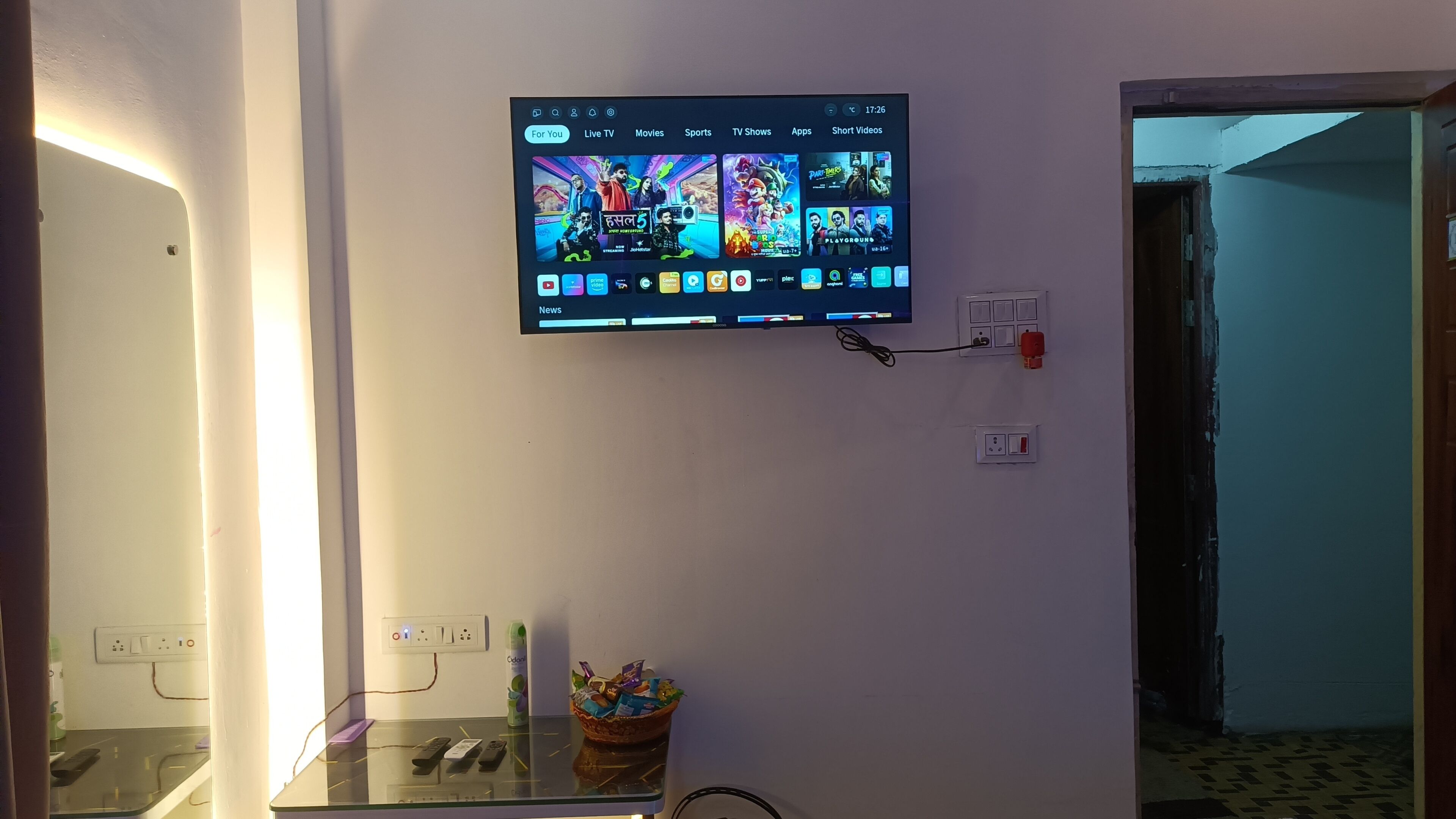 Un televisor montado en la pared mostrando diversas opciones de entretenimiento.