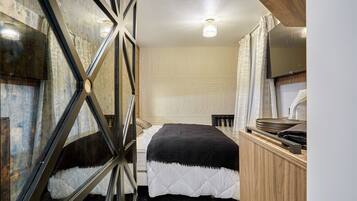Un dormitorio con una cama, un armario de madera, una televisión y un papel tapiz estampado.