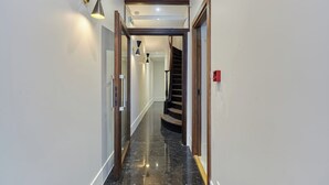 Ein Flur mit poliertem schwarzen Boden, einer Holztreppe und modernen Wandleuchten.