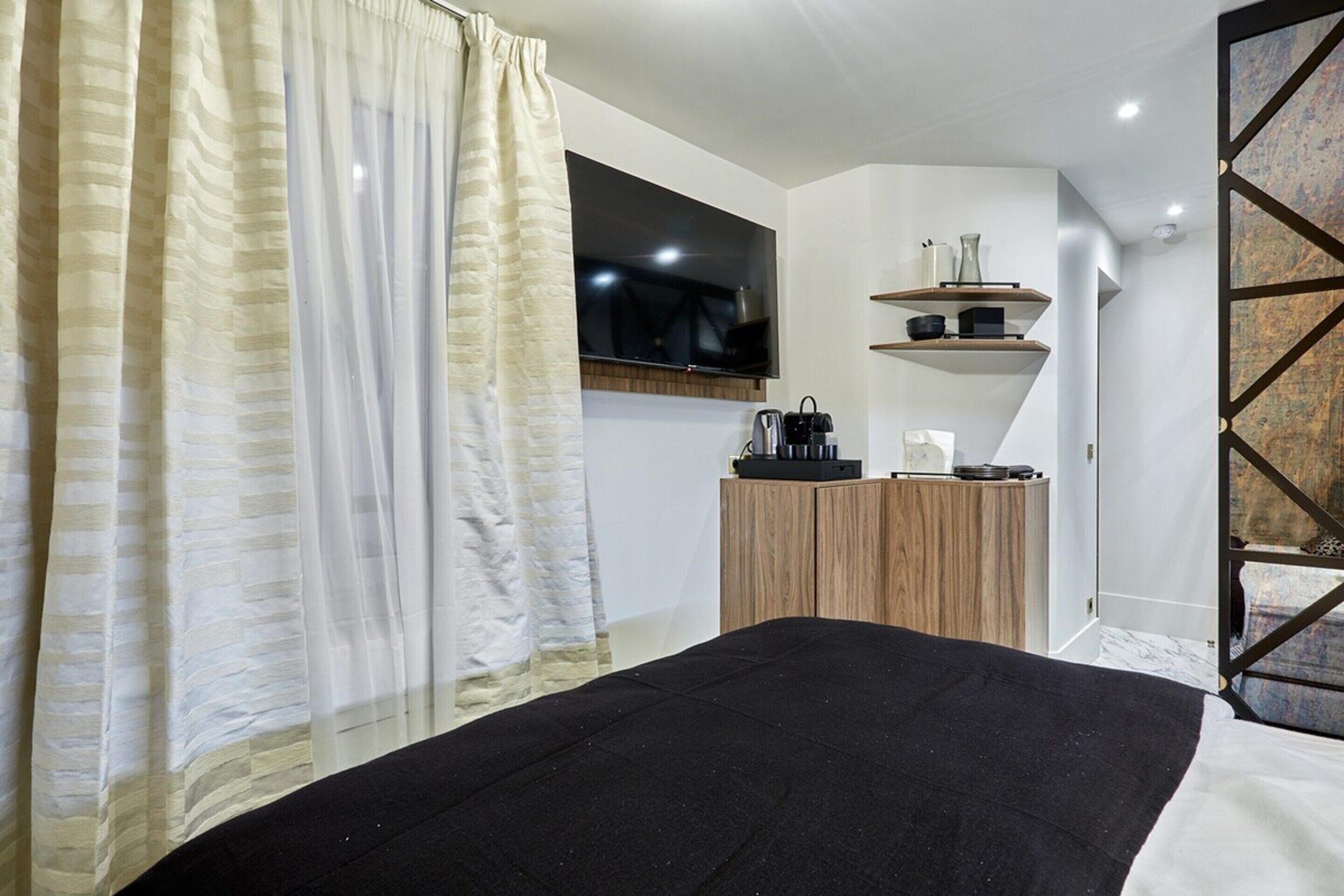 Ein modernes Schlafzimmer mit einem Bett, einem an der Wand montierten Fernseher und einer Holzkabine mit Regalen.