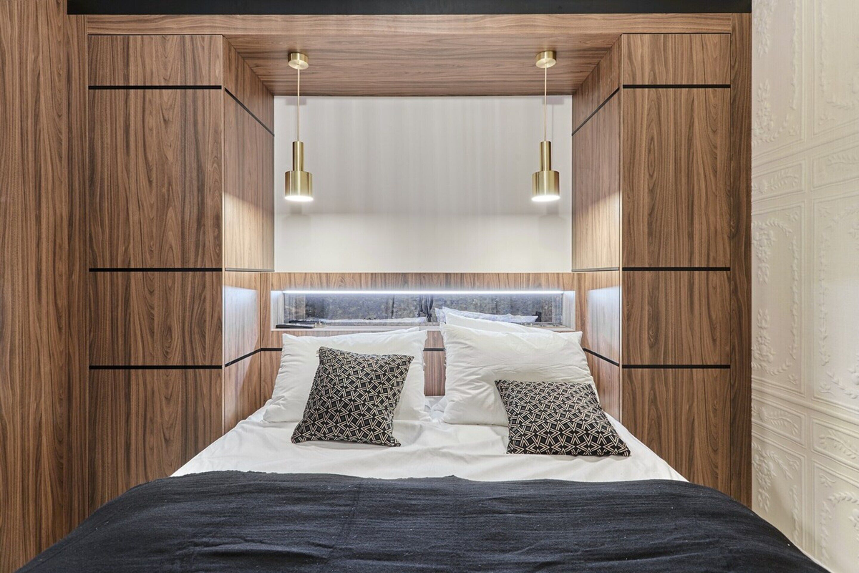 Een slaapkamer met een bed, kussens en een hoofdbord.