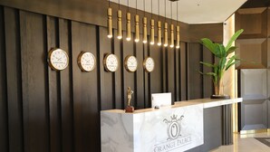 A reception desk with clocks displaying times from various cities, a trophy, and a potted plant. - ORANGE PALACE ESKİŞEHİR (Eskisehir)