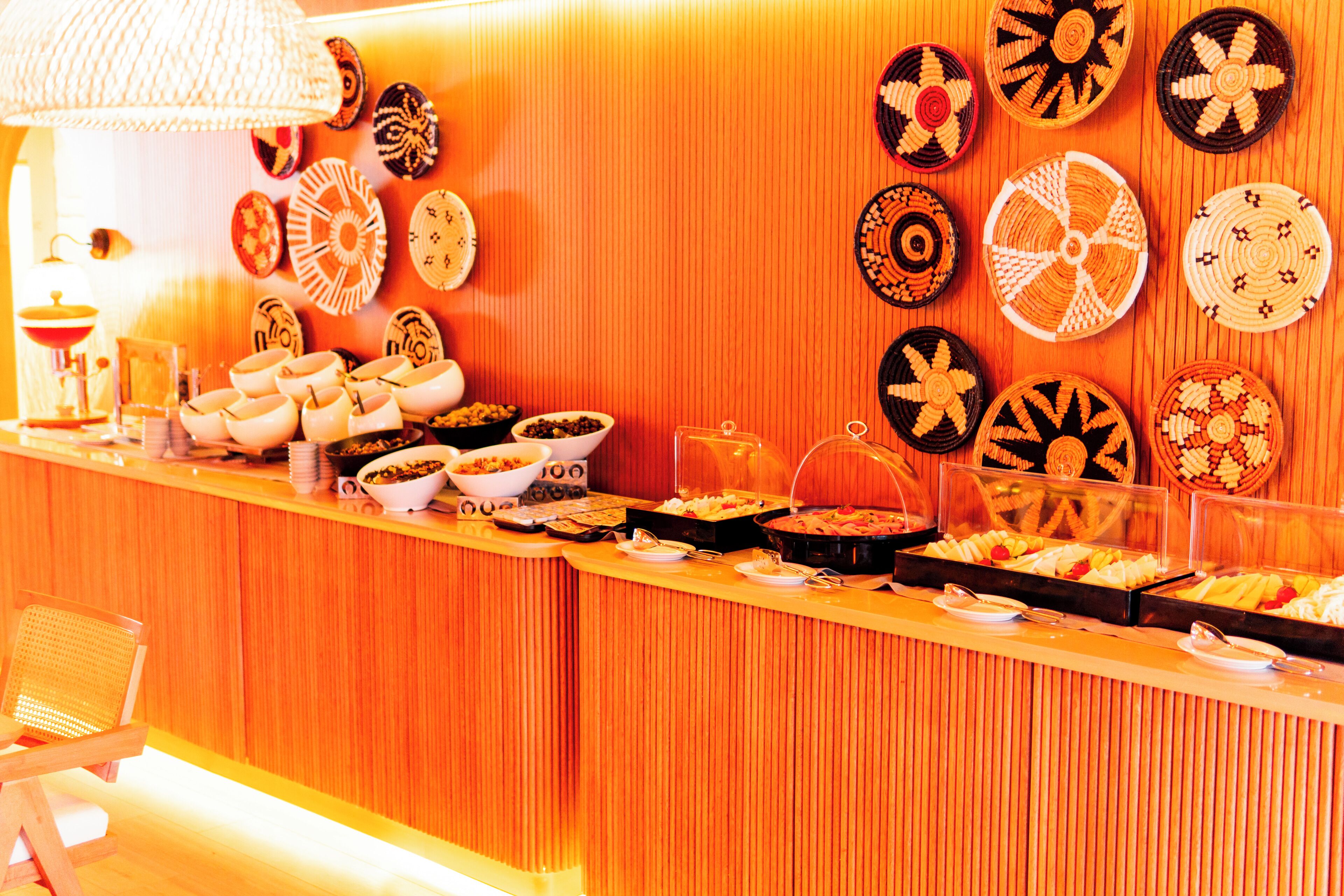 A buffet with various food items and decorative plates on the wall.