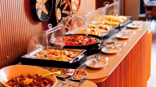 A buffet with various food items and a wall decorated with woven plates. - ORANGE PALACE ESKİŞEHİR (Eskisehir)