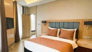 A modern hotel room with a large bed, a flat-screen TV, and a sliding door to the balcony. - ORANGE PALACE ESKİŞEHİR (Eskisehir)