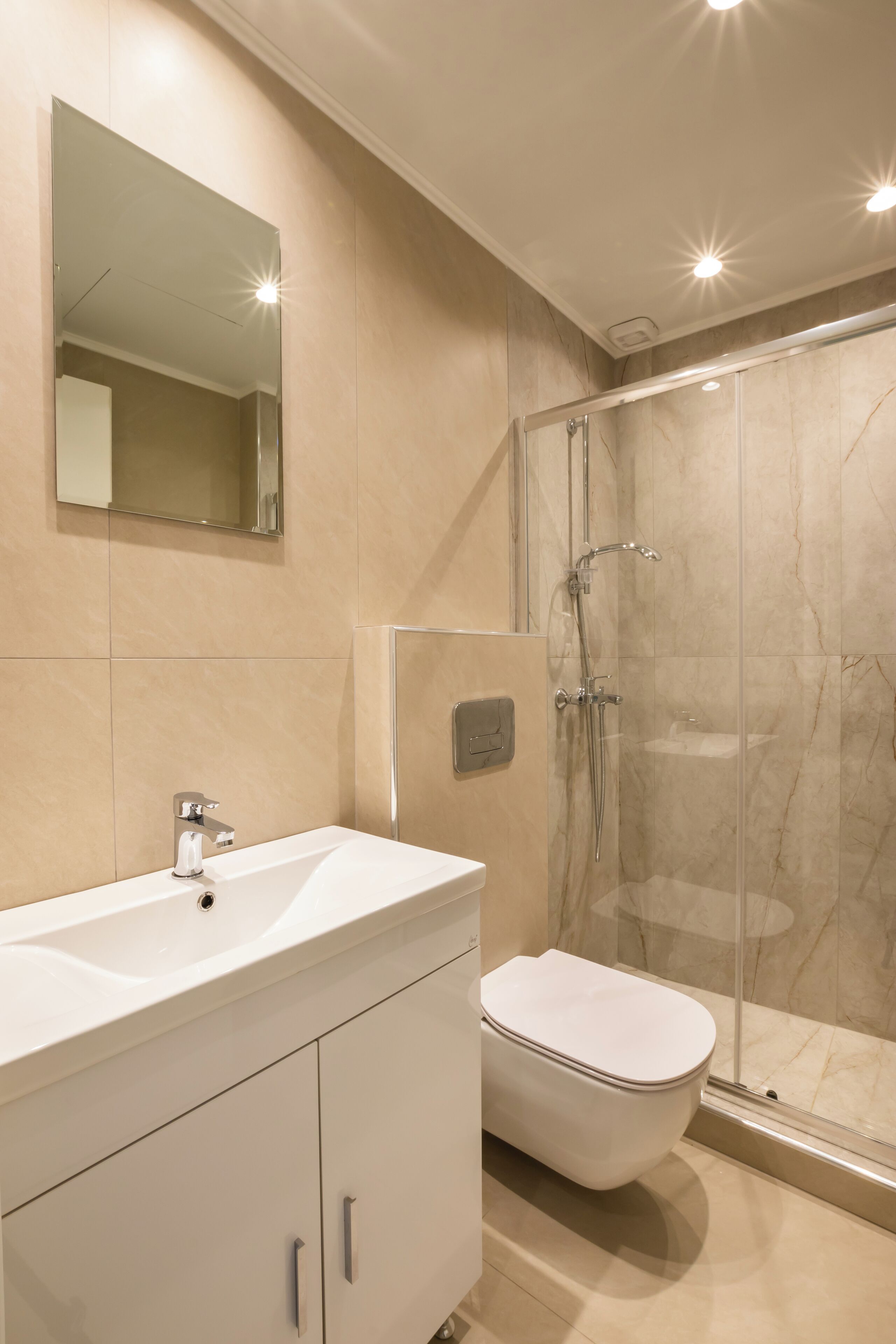 A modern bathroom with a white sink, mirror, and toilet.