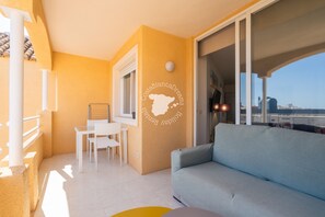 Un balcon avec un canapé, une table et des chaises, une fenêtre et un mur orné d’une carte et de texte.