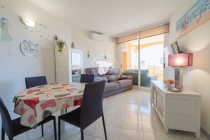 Un coin repas avec une table dressée pour deux personnes, un canapé et une lampe sur une table d’appoint.